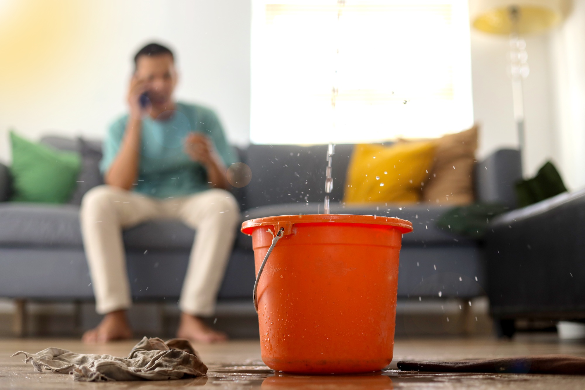 Stressed Young Man Calling Home Service to Repair Roof Leak at Home